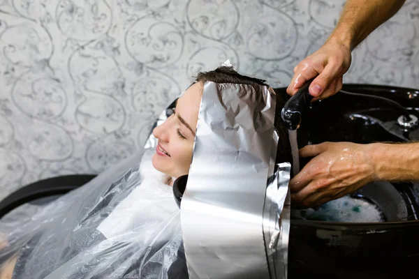 Menina lavar a cabeça em um salão de beleza. Coloração do cabelo, folha metálica — Fotografia de Stock