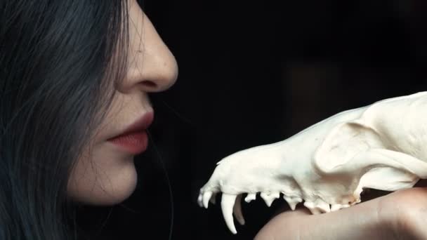 Mysterious young witch whispers a curse and spell holding a skull in the hands of a fox. — Stock Video