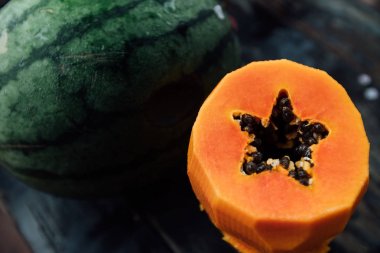 Bütün karpuz ve soyulmuş kesme papaya ahşap bir masaya yalan.