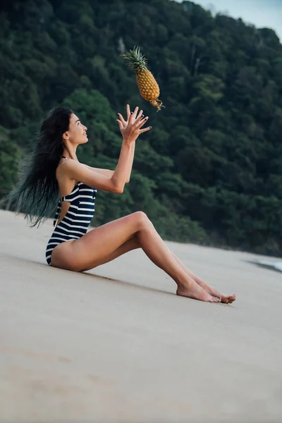 Mulher bonita relaxante em uma praia com abacaxi . — Fotografia de Stock