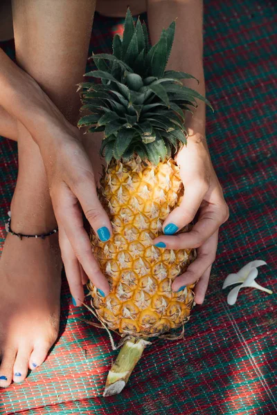 Fata cu o manichiura turcoaz ține un ananas copt în mâinile ei . — Fotografie, imagine de stoc