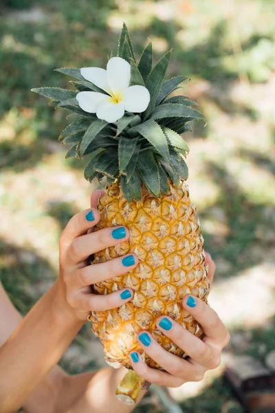 Fata cu o manichiura turcoaz ține un ananas copt în mâinile ei . — Fotografie, imagine de stoc