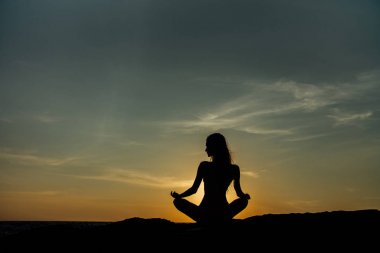 Siluet meditasyon kız lotus pozisyonu çarpıcı deniz arka plan üzerinde taş.