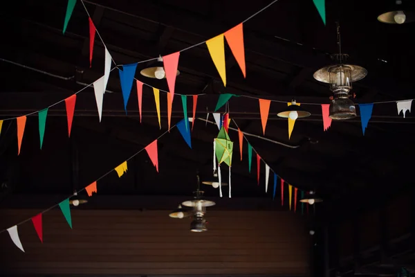 Una cinta con banderas de colores bajo el techo de madera en el bar-restaurante . —  Fotos de Stock