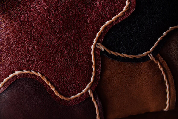 A fragment of a leather bag and a purse made of multi-colored pieces. White leather stitching.