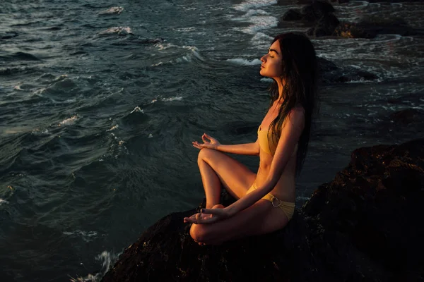 Медитація дівчина лотос позиція на камені на фоні приголомшливого моря . — стокове фото