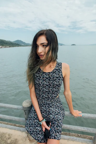 Jovem mulher bonita em vestido sentado no cais e relaxante com céu azul e fundo do mar — Fotografia de Stock