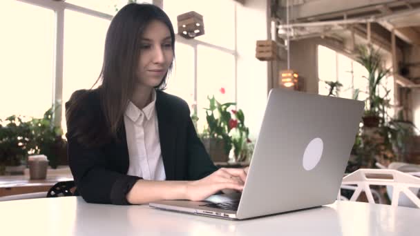 Όμορφη μελαχρινή χρησιμοποιώντας φορητό υπολογιστή στην καφετέρια — Αρχείο Βίντεο
