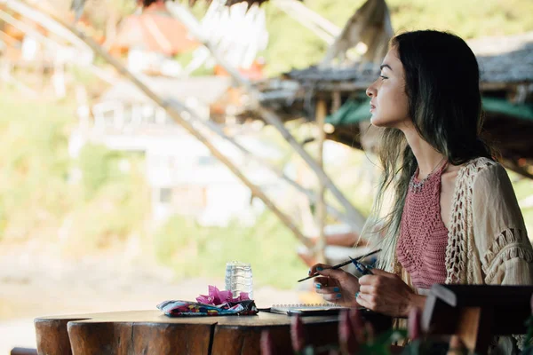 Potret wanita berambut cokelat duduk di meja kayu dan melihat ke kejauhan — Stok Foto