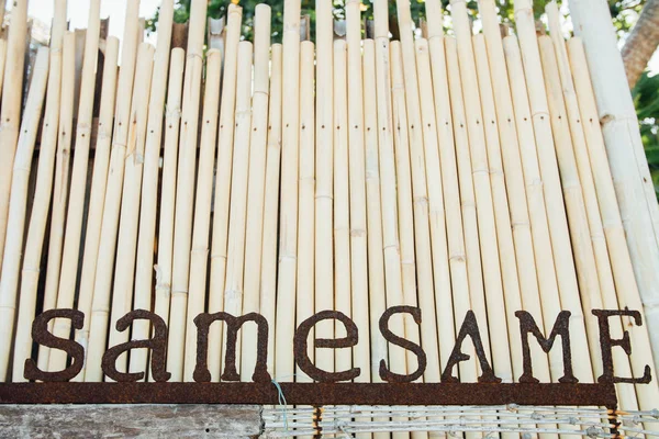Nome vintage da lettere arrugginite in metallo. Vecchie lettere di ferro su sfondo di bambù — Foto Stock
