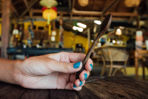 Cucchiaino di legno in una mano delle donne. Cucchiaio di legno in mano ragazza con una manicure blu — Foto Stock
