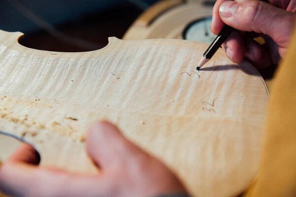Master artisan luthier working on the creation of a violin. painstaking detailed work on wood.