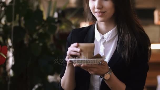 Primo piano di giovani belle mani di donna che tengono e odorano tazza calda di caffè o tè con latte . — Video Stock