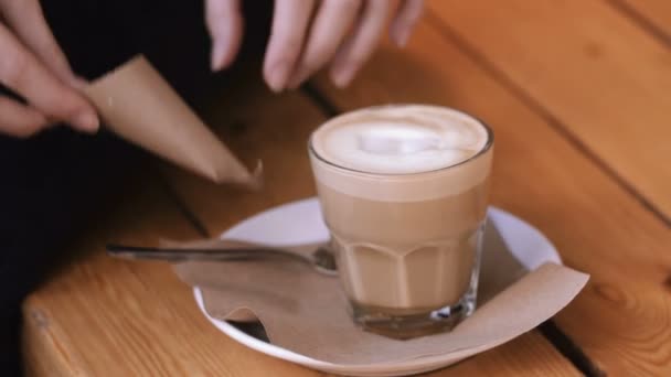Tangan wanita menambahkan gula halus dalam gelas cappuccino di atas piring dan mengaduknya . — Stok Video