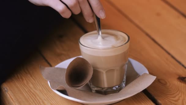 Le mani femminili aggiungono zucchero raffinato in un bicchiere di cappuccino su un piattino e lo mescolano . — Video Stock