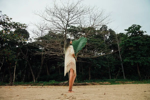 Mulher bonita em túnica na praia com palmeira tropical de folha grande — Fotografia de Stock