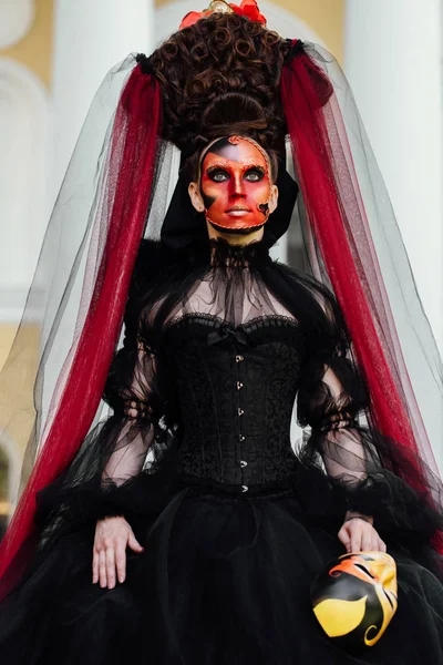 Portret van de heks in zwarte vintage jurk. Vrouw weduwe met rode kunst make-up voor halloween. — Stockfoto