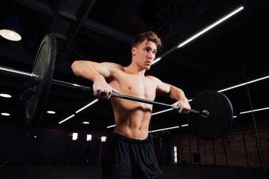 Plaka bar ile spor salonunda egzersiz güçlü adam. Yukarı çeker.