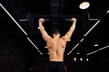 Plaka bar ile spor salonunda egzersiz güçlü adam. Yukarı çeker.