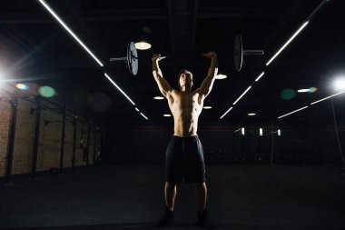 Plaka bar ile spor salonunda egzersiz güçlü adam. Yukarı çeker.
