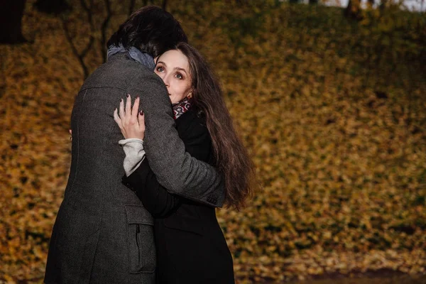 Paar hugs in een park van de val. Gouden herfst op de achtergrond met bladeren en bomen, loof. — Stockfoto