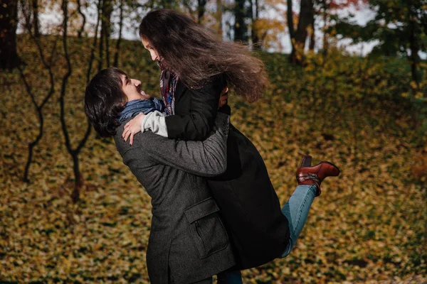 Paar hugs in een park van de val. Gouden herfst op de achtergrond met bladeren en bomen, loof. — Stockfoto