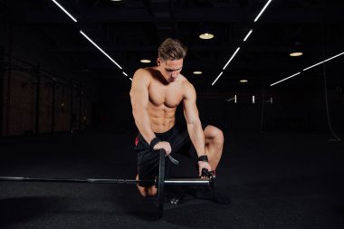 Yakışıklı vücut geliştirmeci adam portresi hazırlamak halter bir spor salonunda egzersiz yapın, halter plaka tutmak için.