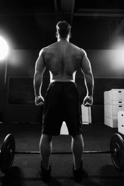 Homem bombeado atlético fisiculturista fica em frente ao bar no ginásio. Fitness macho pronto para trabalhar . — Fotografia de Stock