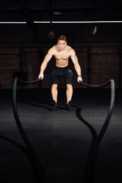 Fitness cvičení člověka s bitvou lana v tělocvičně. cvičení namontován tělo v klubu. Torzo. — Stock fotografie