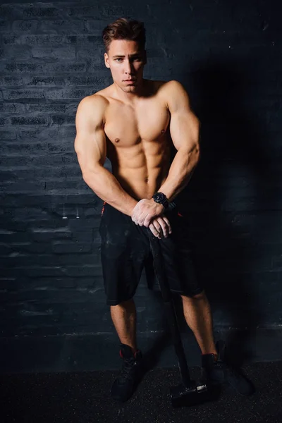 Retrato de um jovem homem fisicamente apto treino no ginásio com martelo. atlético muscular  . — Fotografia de Stock