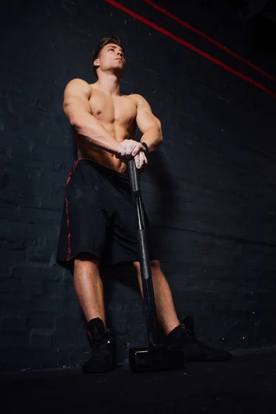 Retrato de un joven en forma física entrenamiento de hombre en el gimnasio con martillo. atlético muscular  . — Foto de Stock