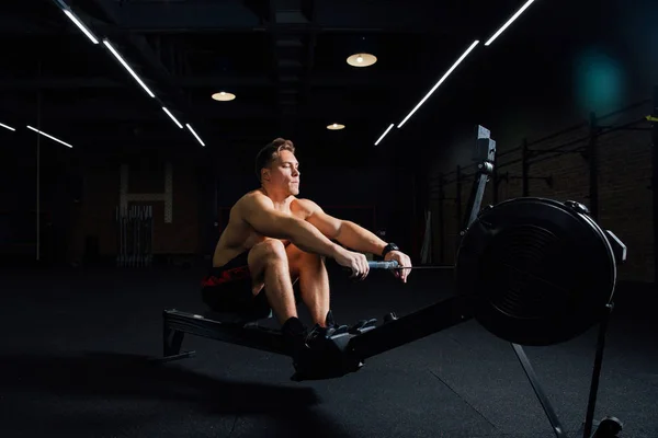 Fitness jeune homme utilisant la machine à ramer dans la salle de gym — Photo