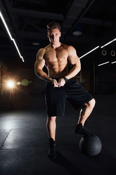Hombre musculoso confiado haciendo empujar hacia arriba desde la pelota MEDICINE en el gimnasio . — Foto de Stock