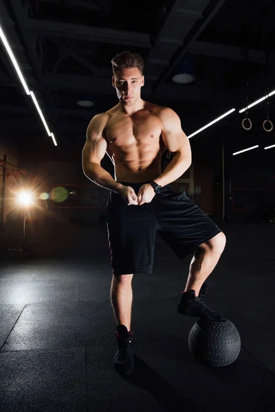 Zelfverzekerde gespierde man doen push up van bal van de geneeskunde in sportschool. — Stockfoto