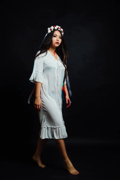 Retrato de uma bela menina asiática sangrenta no Halloween. Roupão branco, coroa étnica de flores . — Fotografia de Stock