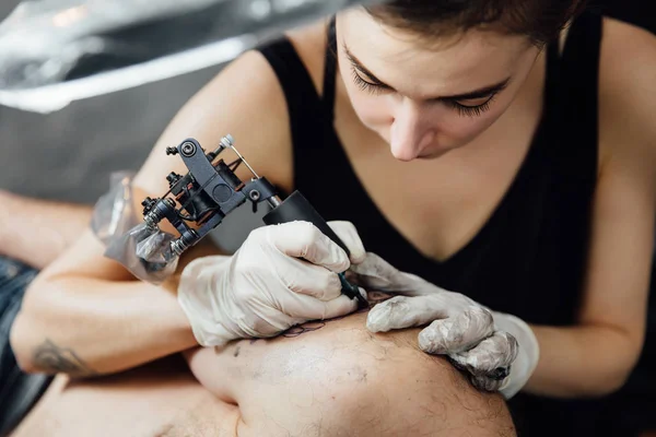 Ritratto ravvicinato del maestro del tatuaggio della ragazza nel processo di realizzazione del tatuaggio con macchina sulla spalla dell'uomo del cliente — Foto Stock