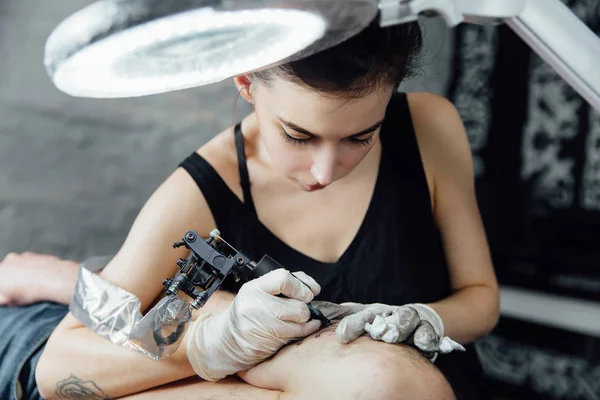 Retrato frontal cercano del hombre acostado en el sofá con el brazo debajo de la cabeza, cliente del salón de tatuajes en proceso  . —  Fotos de Stock