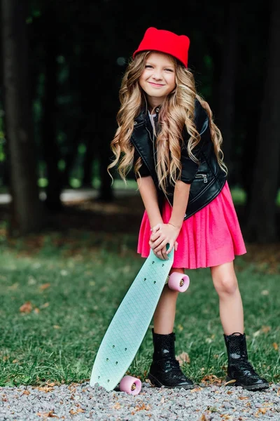 Portrait élégant petite fille de mode posant avec skateboard sur le parc de la ville . — Photo