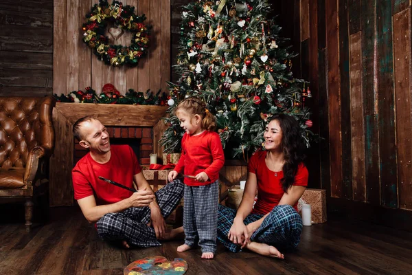 Pijama ailesi bir Noel ağacı ve bir şömine yanındaki çalış. — Stok fotoğraf