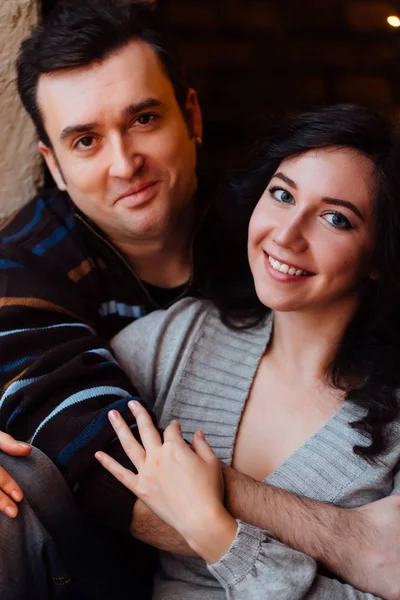 Un par de amantes abrazos sentados en el alféizar de la ventana en el estudio del loft de Navidad. chico está abrazando a la chica . —  Fotos de Stock