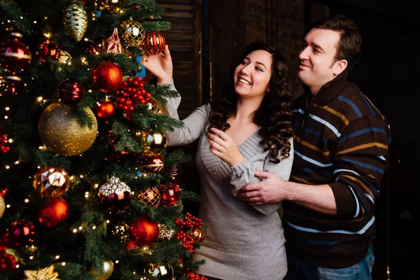 Fiatal pár szerelmes díszíti a karácsonyfát otthon — Stock Fotó