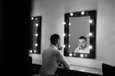 Aynaya bakarak Beyaz gömlekli yakışıklı genç adam portresi.