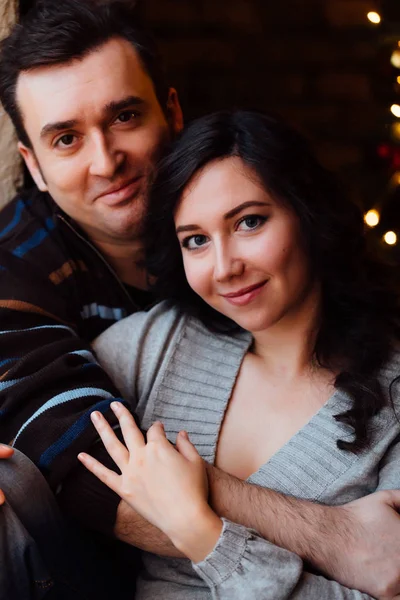 Пара влюблённых обнимается на подоконнике в рождественской студии. парень обнимает девушку . — стоковое фото