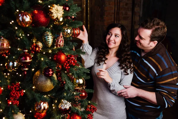 Pareja joven enamorada decora un árbol de Navidad en casa —  Fotos de Stock