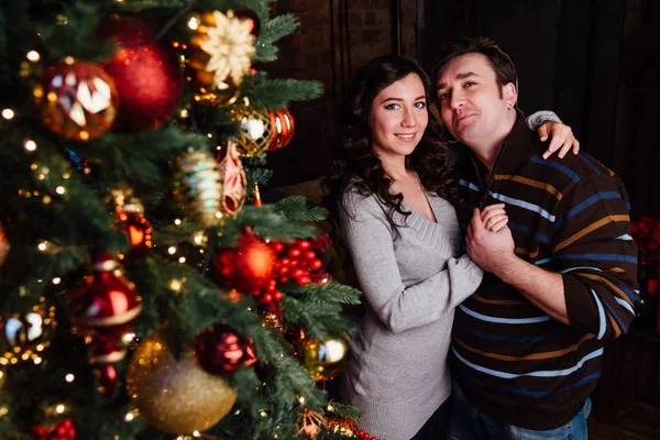 Pareja joven enamorada decora un árbol de Navidad en casa —  Fotos de Stock