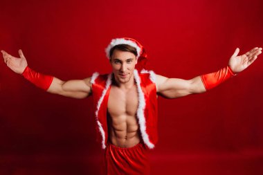 Noel tatili. seksi güçlü santa claus şapka takıyor. Genç kaslı adam. kırmızı bir arka plan.
