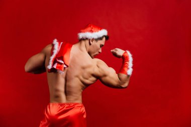Noel tatili. seksi güçlü santa claus şapka takıyor. Genç kaslı adam. kırmızı bir arka plan.