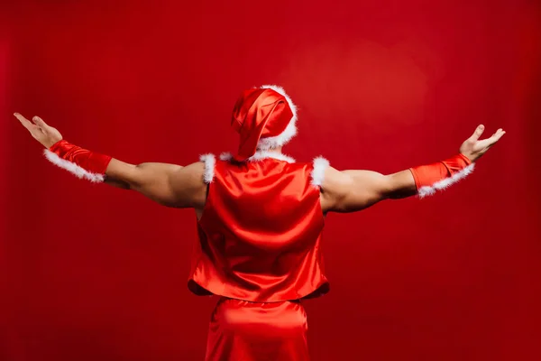 Kerstvakantie. sexy sterke Kerstman hoed dragen. Gespierde jongeman. rode achtergrond. — Stockfoto