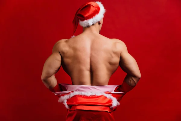 Noel tatili. seksi güçlü santa claus şapka takıyor. Genç kaslı adam. kırmızı bir arka plan.