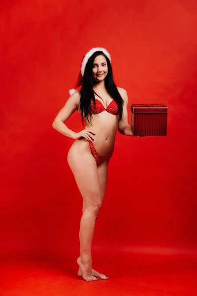 Navidad, vacaciones de Año Nuevo.. Sexy chica hermosa deportes en bikini santa claus con caja de regalo — Foto de Stock